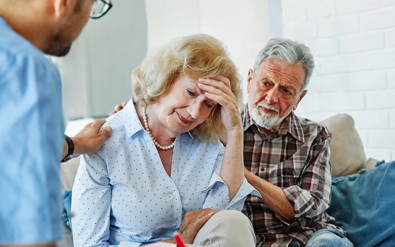 אישה מתוסכלת מסתכלת לרצפה בזמן שבעלה והרופא תומכים בה