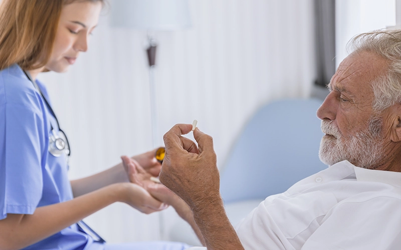 מטופל בפאלאס שוכב במיטה ומחזיק כדור שהמטפלת שלו מביאה לו